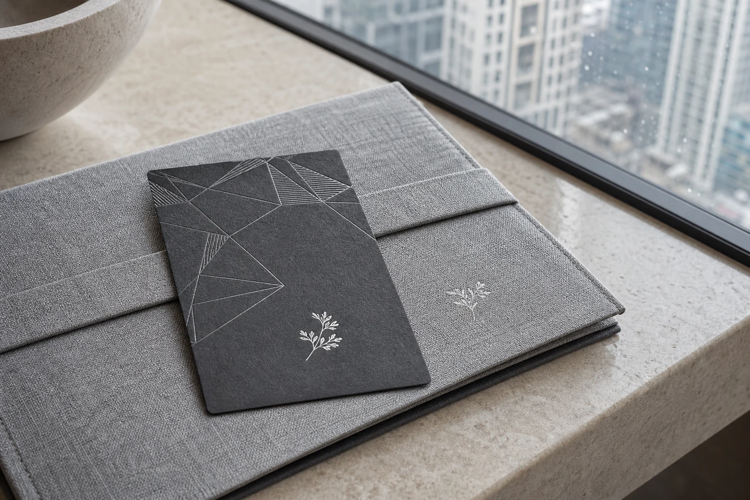 Charcoal paper hotel key card with silver foil geometric design by a city hotel window